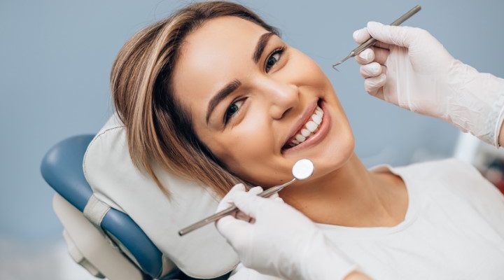 portrait of young female with perfect smile portrait of young caucasian woman with perfect smile in dental office, come to treat spoiled teeth, look at camera